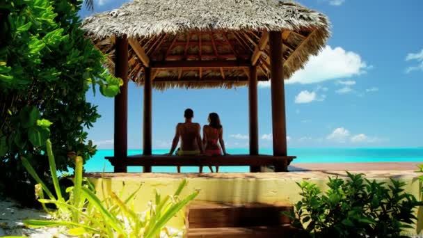 Paar in reetgedeckter Tiki-Hütte am Strand — Stockvideo