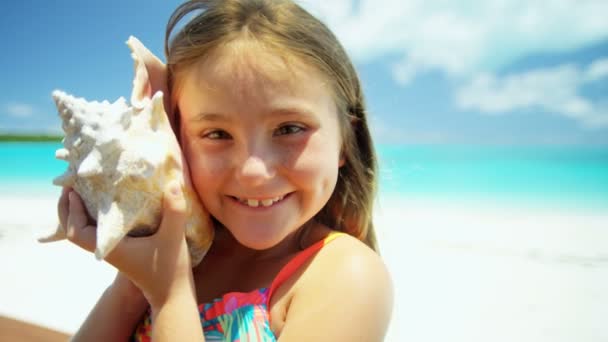 Niña en una playa sosteniendo una concha — Vídeo de stock