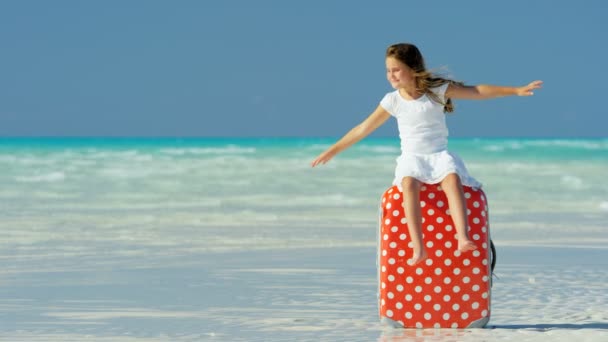 Little girl on a beach sitting on a suitcase — Stock Video