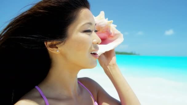 Kinesisk flicka håller seashell på tropical beach — Stockvideo