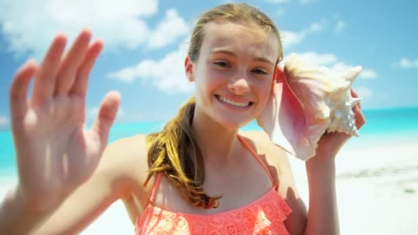 Tienermeisje op een strand met een schelp — Stockvideo