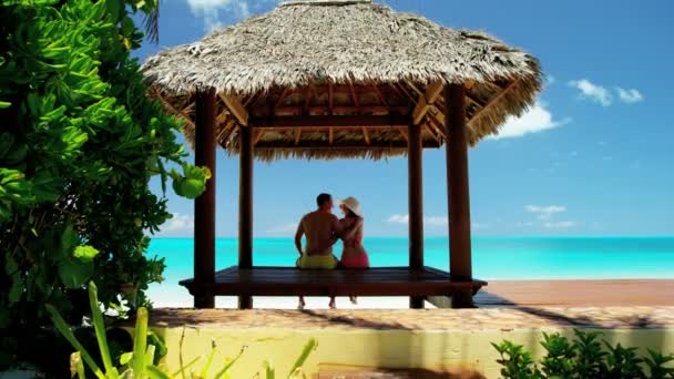 Paar in reetgedeckter Tiki-Hütte am Strand — Stockvideo