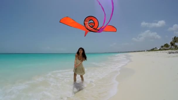 Азиатская девушка играет с красным змеем на пляже — стоковое видео