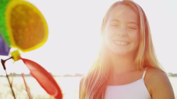 Girl outdoors playing with colorful windmill toy — Stock Video