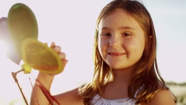 Meisje buiten spelen met kleurrijke windmolen speelgoed — Stockvideo