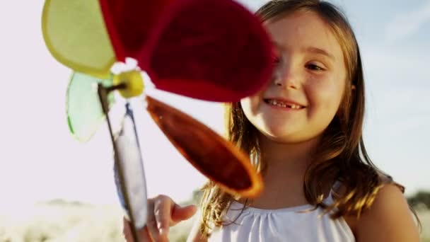 Malá holčička v louce hraje s hračkou větrný mlýn — Stock video