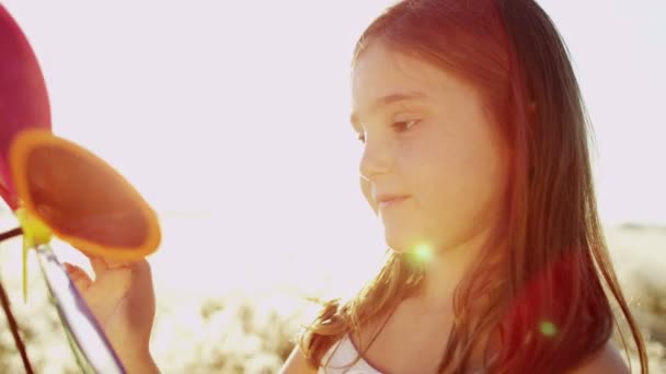 Petite fille dans prairie jouer avec moulin à vent jouet — Video