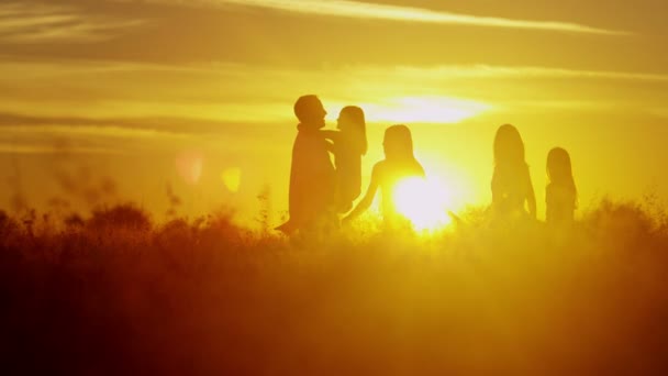 Föräldrar med döttrar på ängen vid solnedgången — Stockvideo