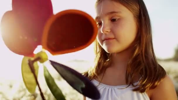 Niña en el prado jugando con el juguete del molino de viento — Vídeos de Stock