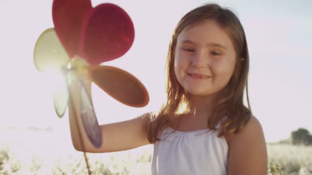 Niña en el prado jugando con el juguete del molino de viento — Vídeos de Stock