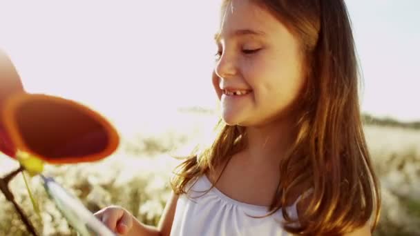 Dziewczyna gra na zewnątrz z wiatrak kolorowe zabawki — Wideo stockowe