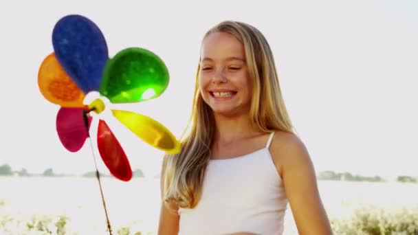 Chica al aire libre jugando con colorido molino de viento juguete — Vídeo de stock