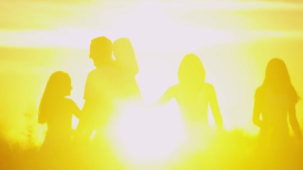 Föräldrar med döttrar i ängen vid solnedgången — Stockvideo