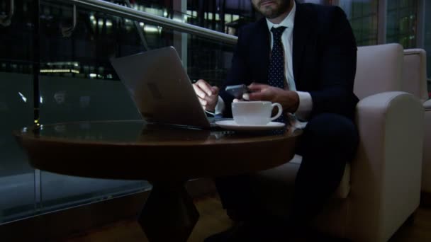 Homem de negócios trabalhando com laptop e telefone inteligente à noite — Vídeo de Stock