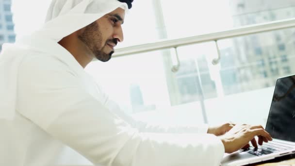 Businessman in traditional dress working on laptop — Stockvideo