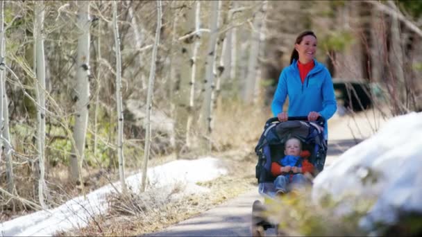 Madre con figlio in passeggino godendo passeggiata nel parco — Video Stock