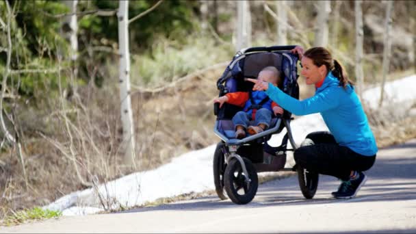 Mother with son in pushchair enjoying walk in park — Stock Video