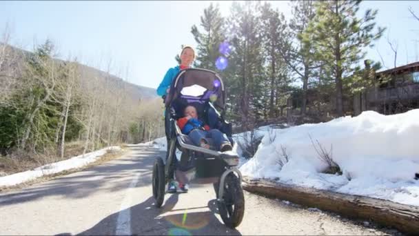 Madre con hijo en cochecito disfrutando caminar en parque — Vídeos de Stock