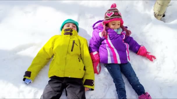 Niños haciendo ángeles de nieve — Vídeos de Stock