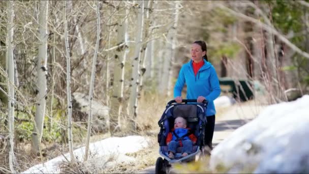 Moeder met zoon in kinderwagen uitgevoerd in park — Stockvideo