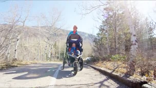 Mother with son in pushchair enjoying walk in park — Stock Video