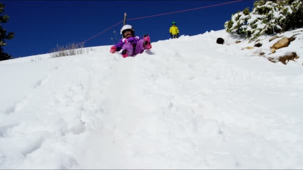 Niño y niña jugando en diapositiva de nieve — Vídeos de Stock