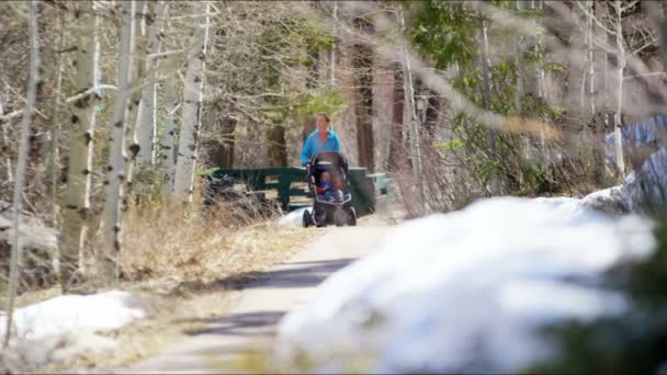 Mamma med son i sittvagn njuter av promenad i park — Stockvideo