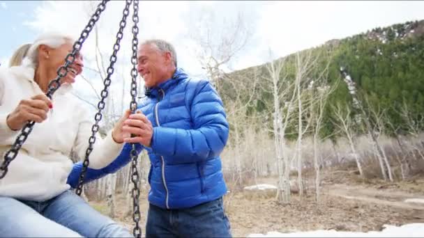 Пожилая пара качается на качелях на открытом воздухе — стоковое видео