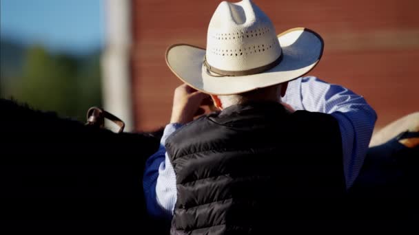 Cowboy in corral saddling his horse — Stock Video
