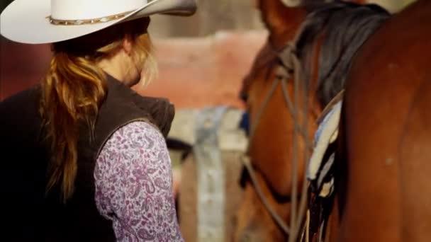Cowgirl i corral sadla sin häst — Stockvideo