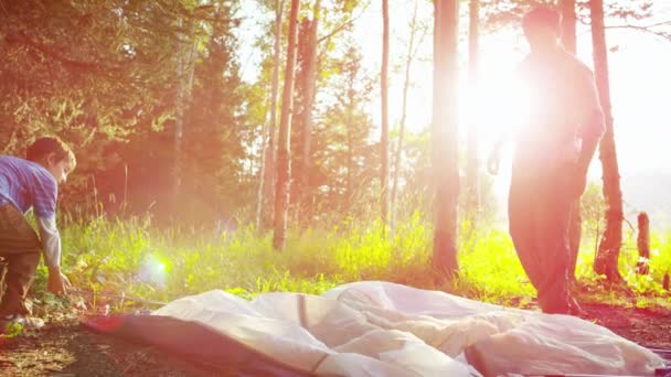 Boy learning assemble tent with father — Stock Video