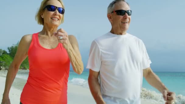 Feliz casal americano sênior desfrutando de exercício pela costa — Vídeo de Stock