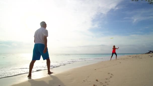 Pareja activa jubilada entrenando a Frisbee por océano Bahamas — Vídeo de stock