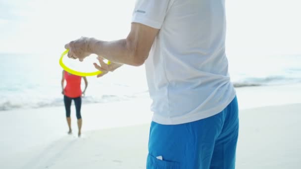 Saludable senior caucásico pareja jugando frisbee juguete caribe — Vídeos de Stock