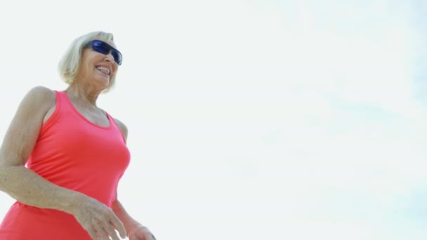Érett nő élvezi nyugdíj játszik strand Frisbee játék — Stock videók