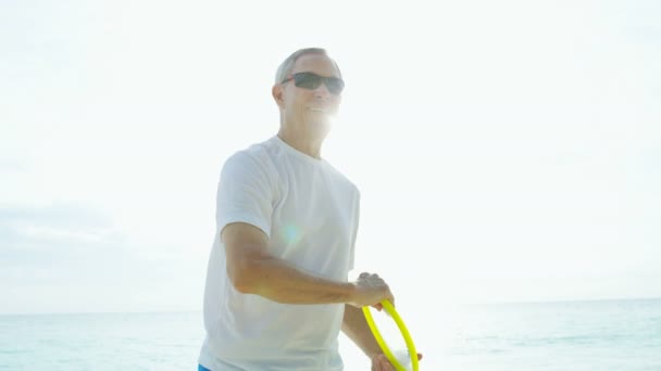 Moden mand nyder pensionering på stranden spiller frisbee – Stock-video