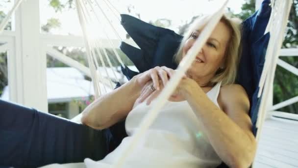 Wanita dewasa yang santai di tempat tidur gantung di teras Bahama — Stok Video