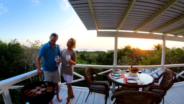 Casal aposentado grelhando carne ao ar livre ao pôr do sol Bahamas — Vídeo de Stock