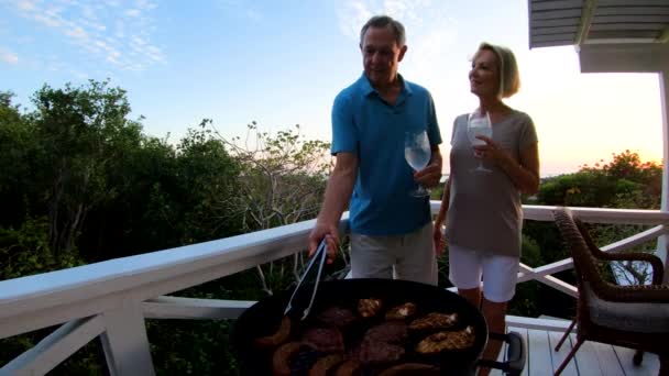 Mayores preparando barbacoa en la terraza al atardecer Bahamas — Vídeo de stock