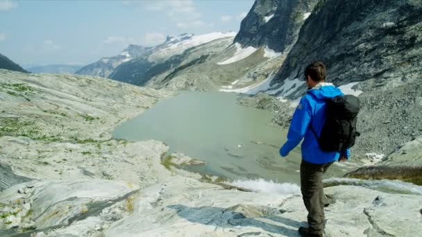 在冰川附近的风景秀丽的山上徒步旅行的白人男女青年 — 图库视频影像