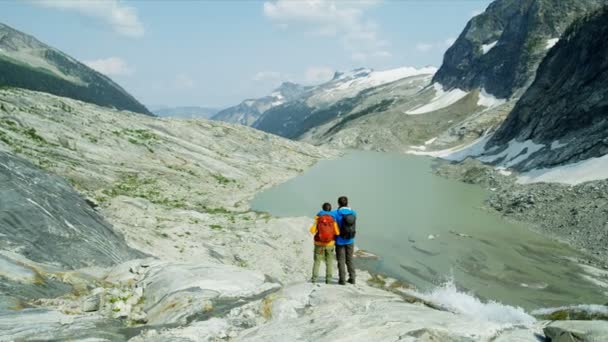 年轻的白种人夫妇在不列颠哥伦比亚省冰川湖畔的荒原上悠闲地徒步旅行 — 图库视频影像