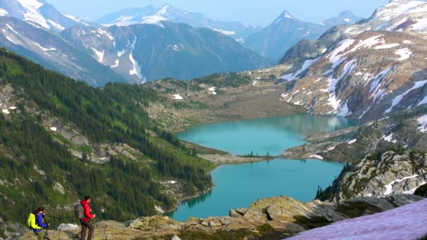 夏の氷河の山の湖の近くを歩く若い冒険的な男性のヘリハイカー ブリティッシュコロンビア — ストック動画