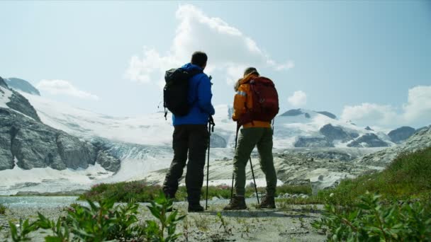 レイクビュー氷河カナダの近くの雪に覆われた山々でハイキングする男性の若い白人の旅行者 — ストック動画