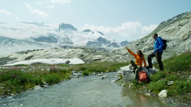 白人男女徒步旅行者在加拿大高山上积雪覆盖的冰河边观赏风景 — 图库视频影像