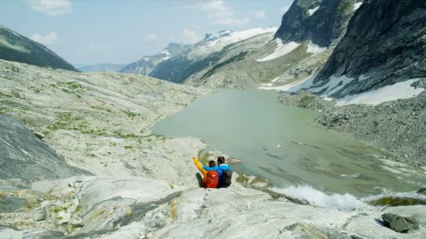Young Active Couple Hiking Extreme Mountain Terrain Relaxing Glacial Lake — Stock Video