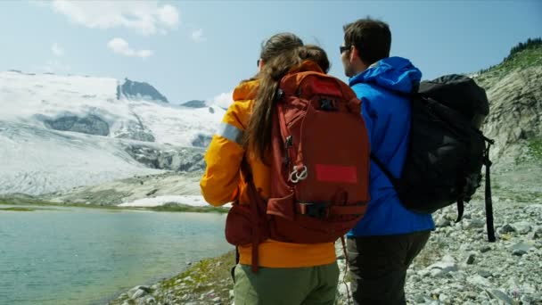 这对白种人夫妇在山野上悠闲自在地观赏着户外的冰川湖和冰川 — 图库视频影像