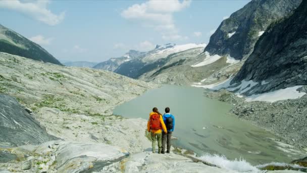 在加拿大艳阳高照下 年轻活跃的登山夫妇在冰湖瀑布附近悠闲自在地远足 感觉很成功 — 图库视频影像