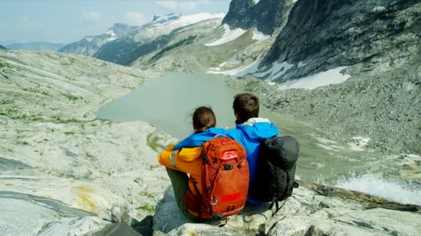 白种人夫妇在极度高山地带徒步旅行 在明媚的阳光下 在冰河瀑布下悠闲自在 — 图库视频影像