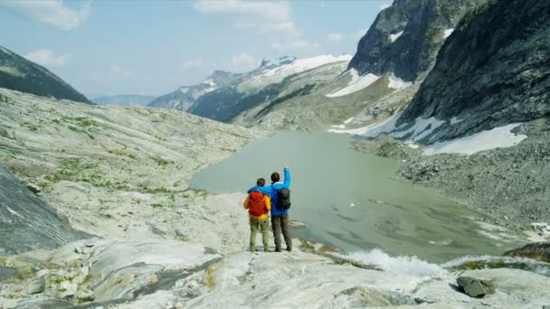 若いヘリの氷河湖の景色男性ハイカー女性白人の冒険旅行者山の風景カナダ — ストック動画