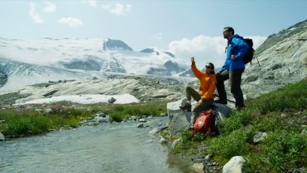 Jovens Caminhantes Heli Masculinos Femininos Que Descansam Perto Rio Glacial — Vídeo de Stock
